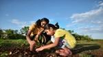 Two children planting a plant in the ground