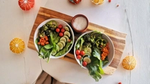 Two bowls of fresh salad on a wooden board.