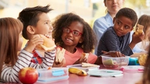 Children sit at a table eating their meal.