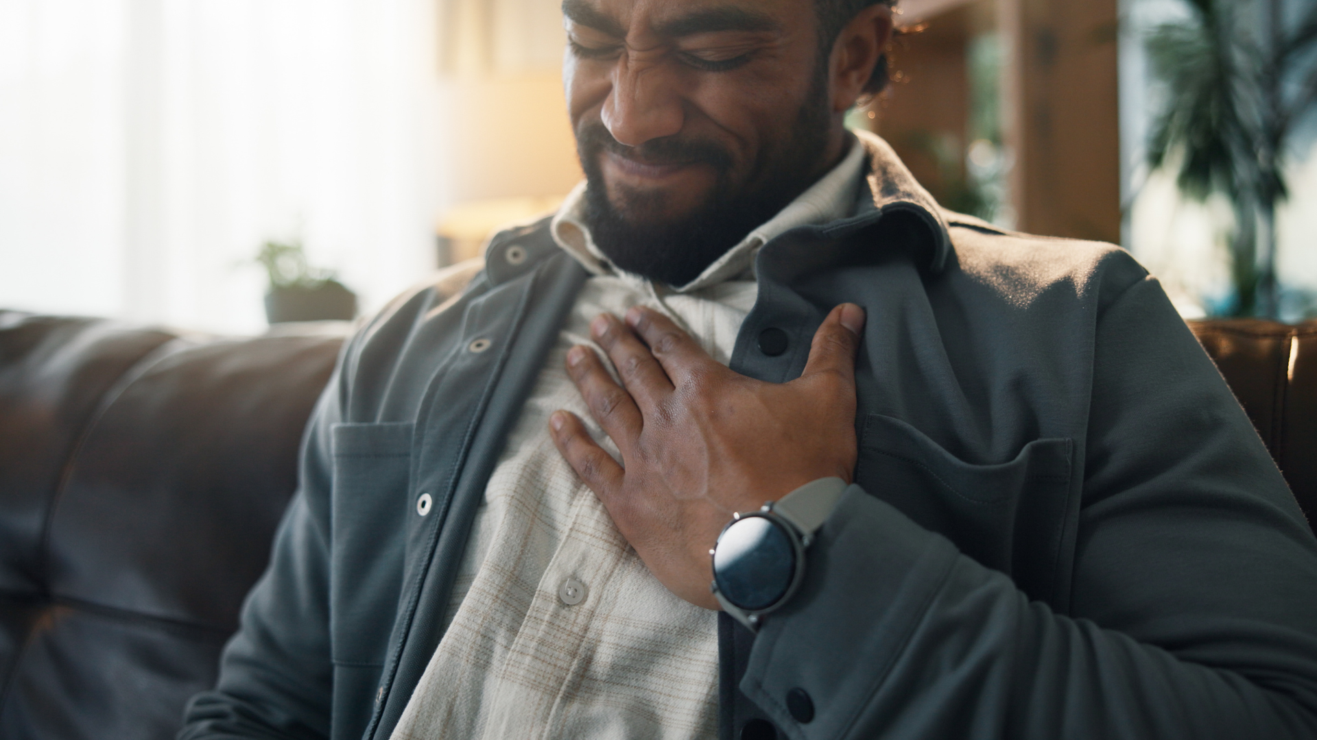 Man pressing hand to chest, grimacing in discomfort.