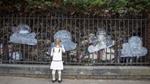 Young girl writing on a paper cloud hanging on a fence