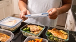 A person putting meals into containers.