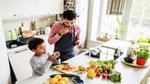 Man and young boy preparing, chopping and snacking on vegetables