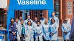Vaseline factory employees gather beneath a large blue Vaseline sign.