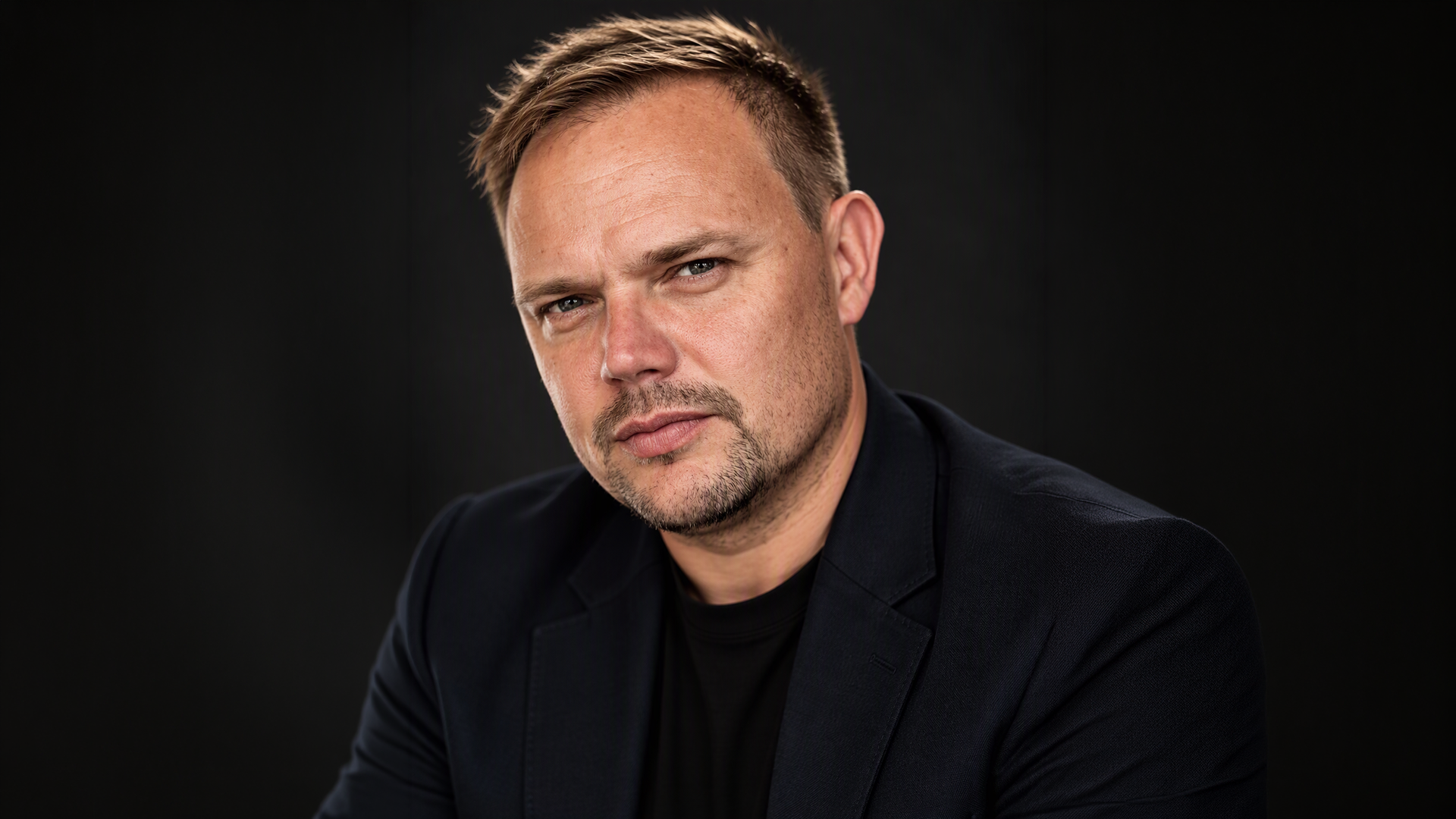 Photo of Jamie Bates, Head of Design for Unilever Personal Care. Jamie is a man with short hair, he is wearing a black shirt.