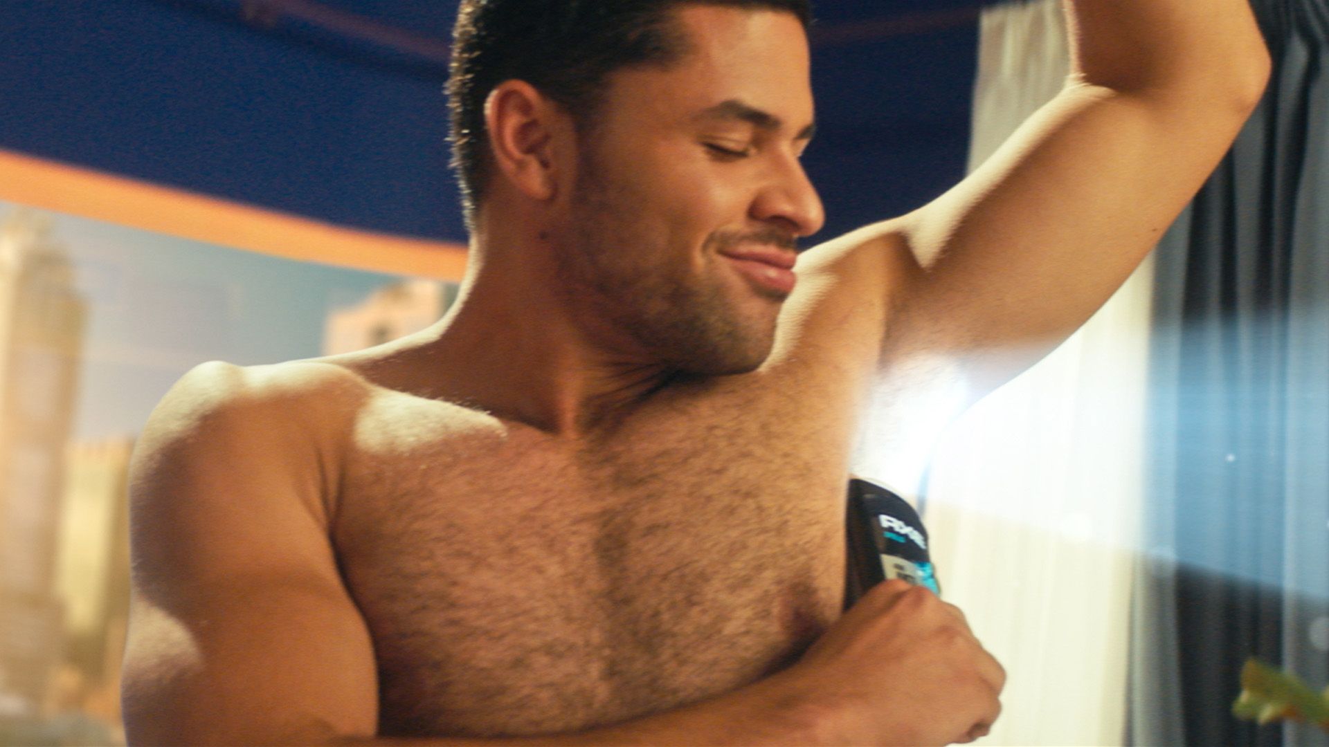 A man applies Axe deodorant to his underarms. A beam of light appears behind him.