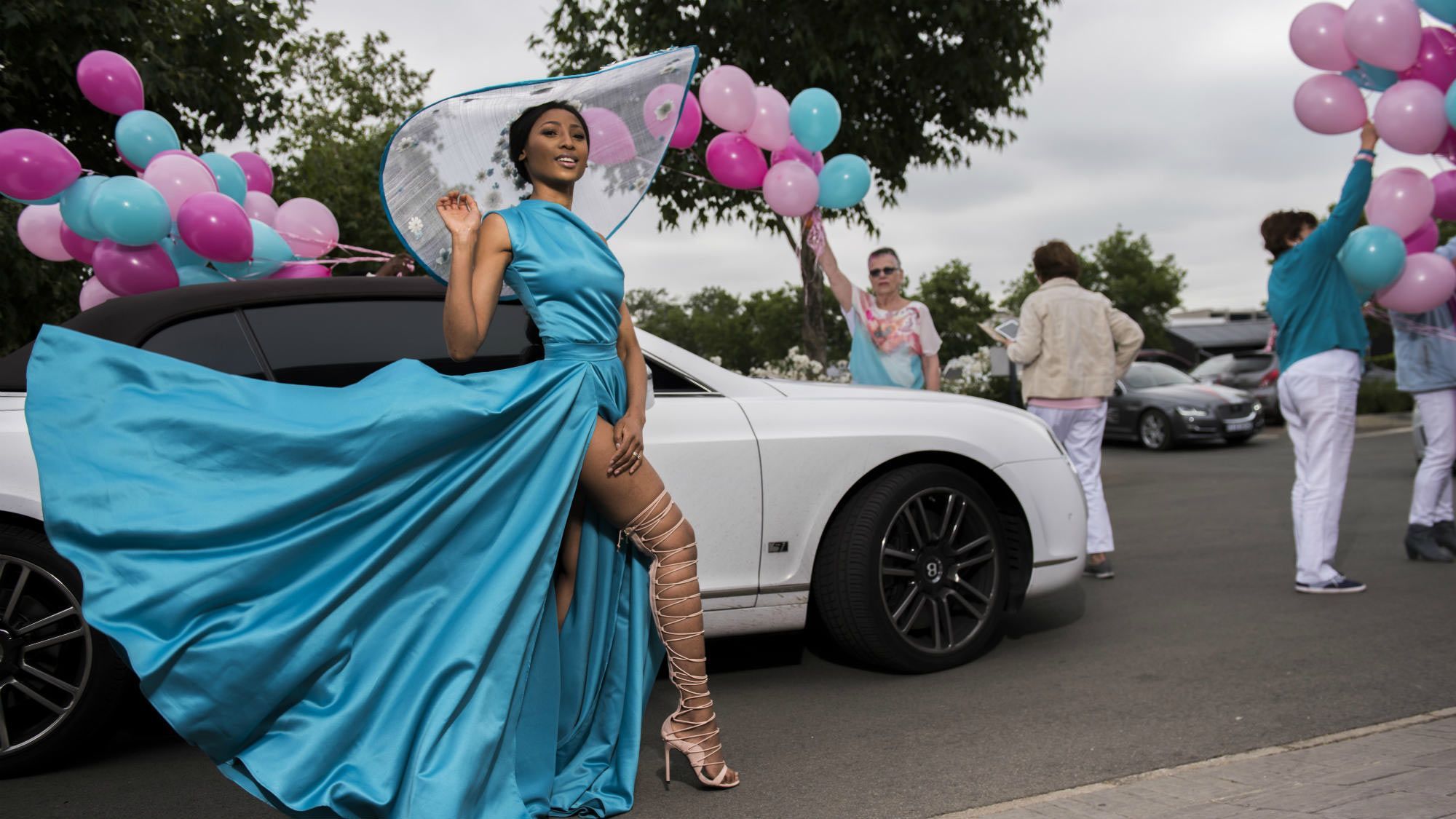 Woman with blue dress standing in front of a car