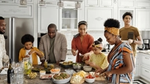 A family is gathered around a kitchen island, preparing a meal.