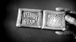 A black and white image of a hand holding an original Lifebuoy bar of soap