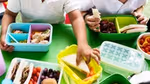 School children taking food out of their lunch boxes.